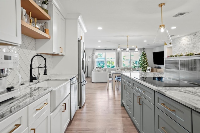 kitchen with light stone countertops, pendant lighting, white cabinetry, sink, and black electric cooktop