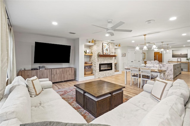 living room with ceiling fan, light hardwood / wood-style floors, and a fireplace