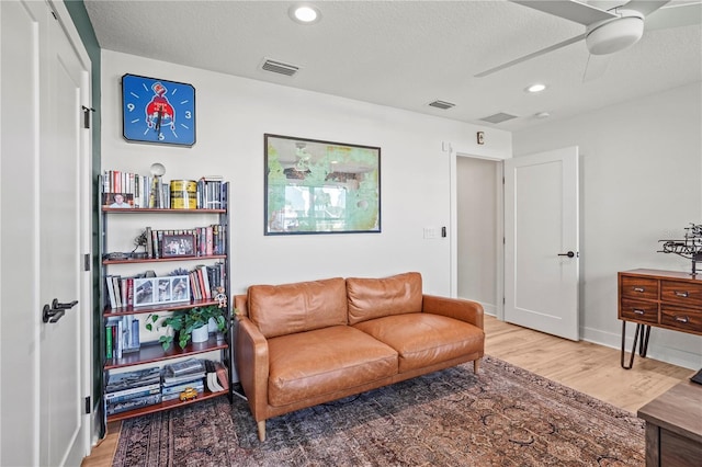 living room featuring ceiling fan, a textured ceiling, and hardwood / wood-style flooring