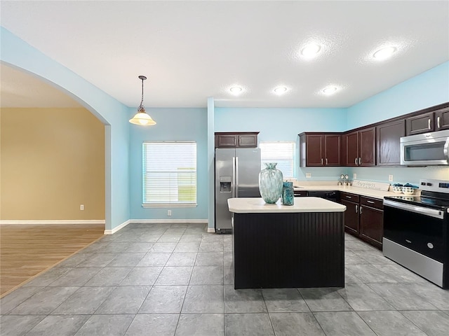 kitchen featuring dark brown cabinetry, a center island, stainless steel appliances, and hanging light fixtures