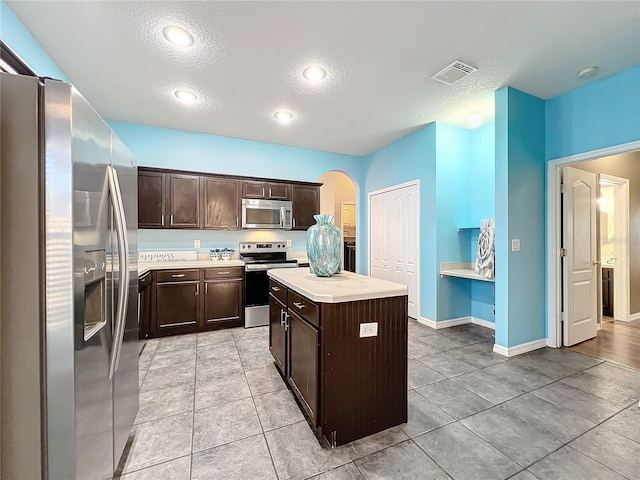 kitchen featuring dark brown cabinets, a kitchen island, stainless steel appliances, and a textured ceiling