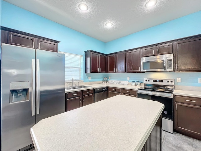 kitchen featuring sink, a center island, a textured ceiling, dark brown cabinets, and appliances with stainless steel finishes