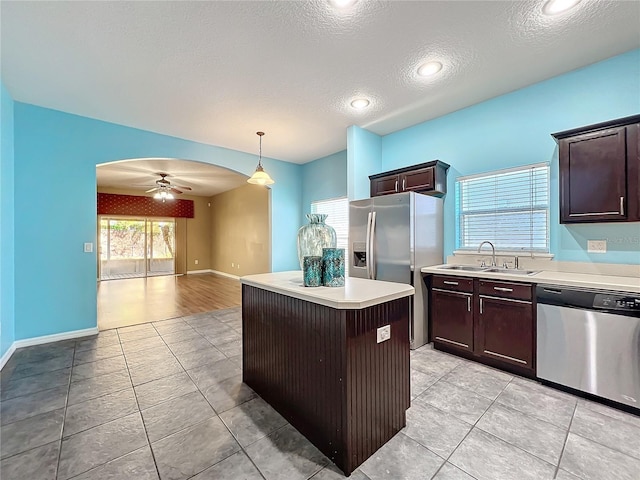 kitchen featuring appliances with stainless steel finishes, ceiling fan, sink, a center island, and hanging light fixtures