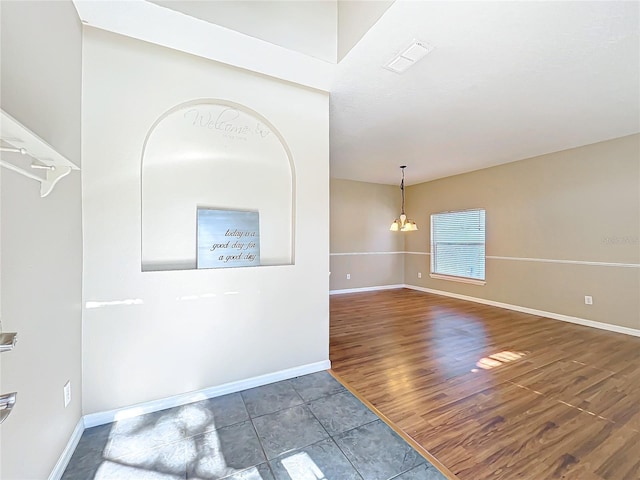 empty room featuring an inviting chandelier and dark wood-type flooring