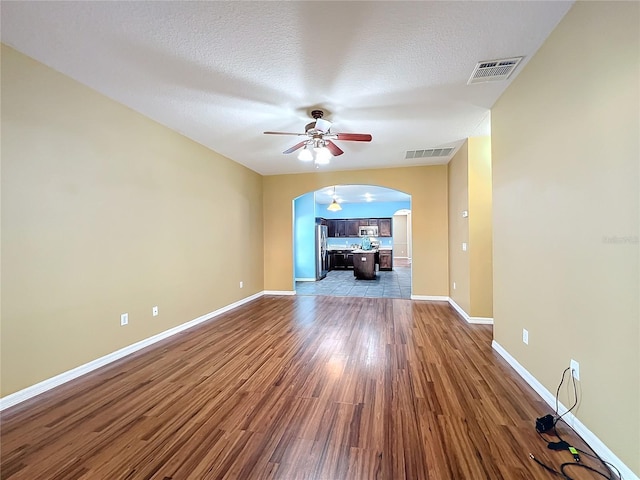 unfurnished living room with ceiling fan, wood-type flooring, and a textured ceiling