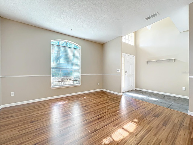 unfurnished room with dark hardwood / wood-style flooring and a textured ceiling