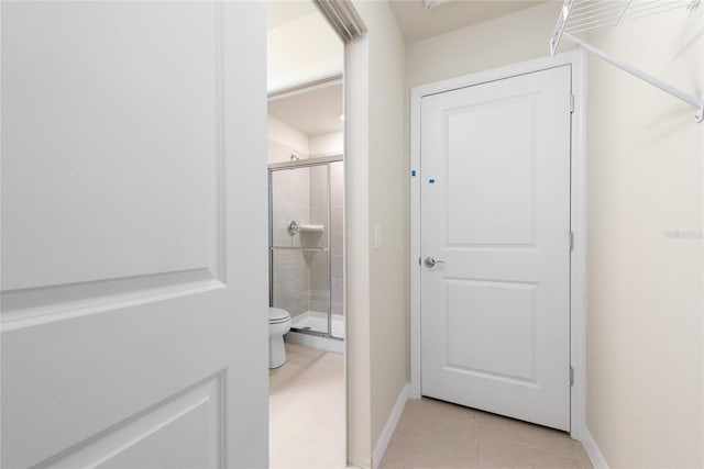 bathroom with tile patterned flooring, toilet, and a shower with door