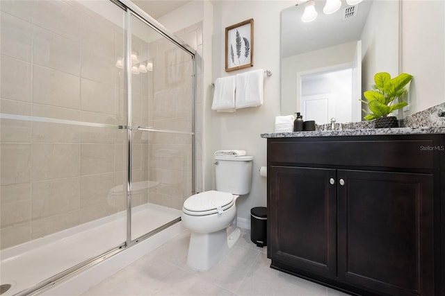 bathroom with tile patterned floors, vanity, an enclosed shower, and toilet