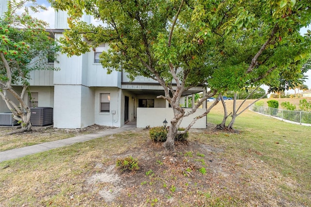 exterior space featuring central air condition unit and a front yard