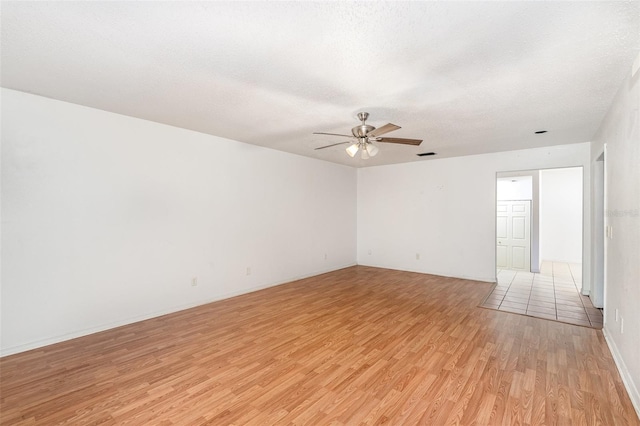 unfurnished room with ceiling fan, light wood-type flooring, and a textured ceiling