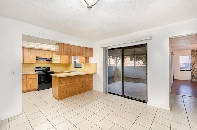 kitchen with light tile patterned flooring, kitchen peninsula, a wealth of natural light, and black electric range