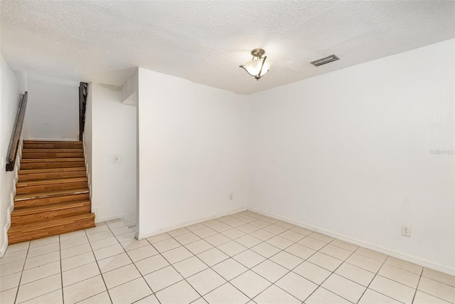 tiled empty room with a textured ceiling