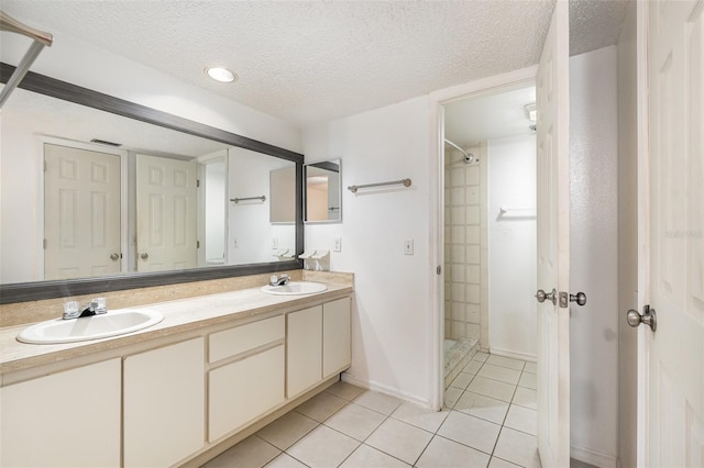 bathroom featuring tile patterned flooring, vanity, tiled shower, and a textured ceiling