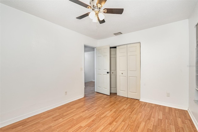 unfurnished bedroom featuring ceiling fan, light hardwood / wood-style floors, a textured ceiling, and a closet