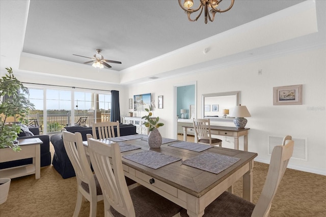 dining area featuring ceiling fan with notable chandelier, carpet floors, and a tray ceiling