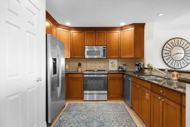 kitchen with backsplash, sink, dark stone countertops, light tile patterned flooring, and stainless steel appliances