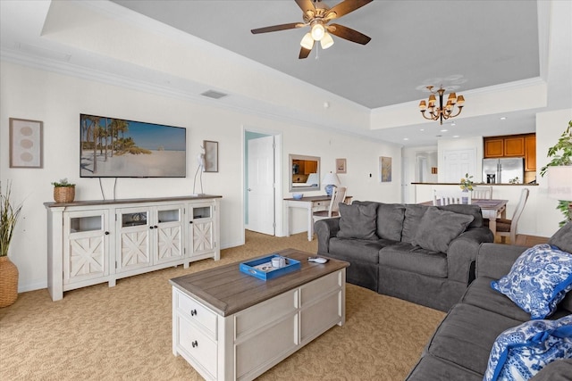 living room featuring a tray ceiling, crown molding, light carpet, and ceiling fan with notable chandelier