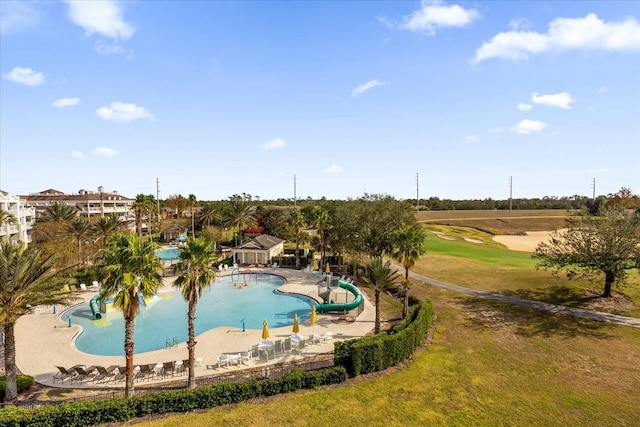 view of pool with a lawn, a water slide, and a patio