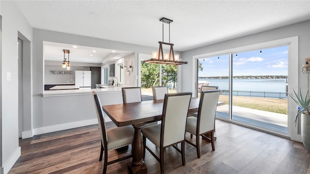 dining space featuring dark hardwood / wood-style flooring, a water view, and a textured ceiling