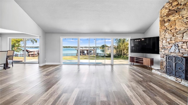 unfurnished living room featuring lofted ceiling, a fireplace, hardwood / wood-style floors, and a textured ceiling