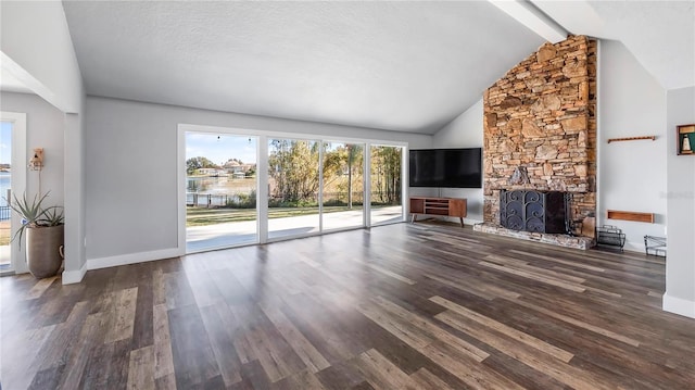 unfurnished living room with a fireplace, dark hardwood / wood-style floors, a textured ceiling, and vaulted ceiling with beams