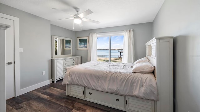 bedroom featuring a water view, dark hardwood / wood-style floors, and ceiling fan