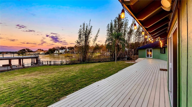 deck at dusk featuring a water view and a lawn