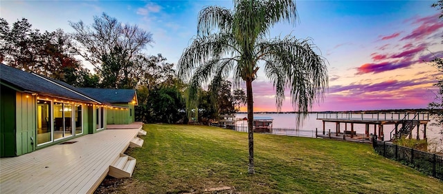 view of dock with a water view and a lawn