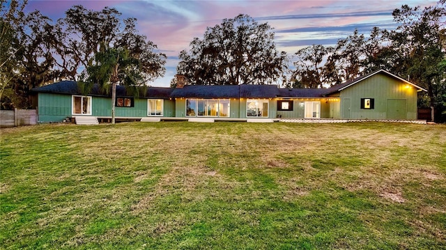 back house at dusk with a lawn