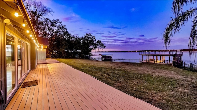 deck at dusk featuring a water view and a yard