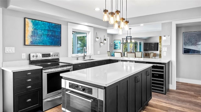 kitchen featuring a kitchen island, sink, a notable chandelier, kitchen peninsula, and stainless steel appliances