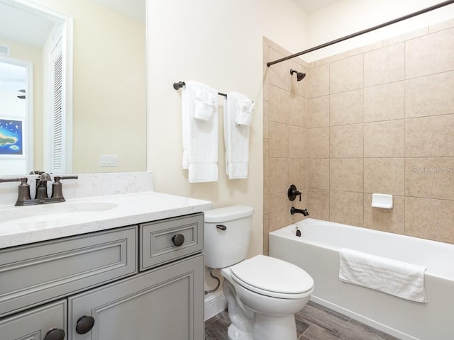 full bathroom with tiled shower / bath combo, toilet, wood-type flooring, and vanity