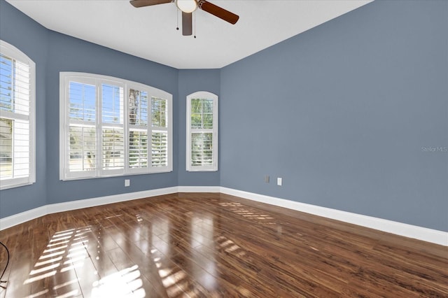 empty room with plenty of natural light, ceiling fan, and wood-type flooring