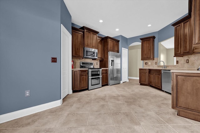 kitchen with decorative backsplash, light tile patterned floors, stainless steel appliances, and sink