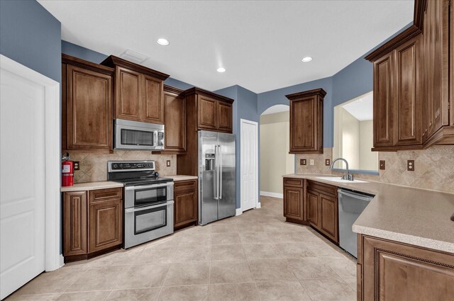 kitchen featuring light tile patterned flooring, appliances with stainless steel finishes, tasteful backsplash, and sink