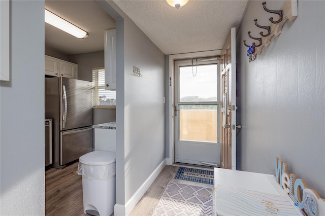 doorway to outside with light hardwood / wood-style floors and a textured ceiling