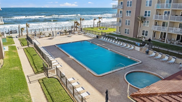 view of pool featuring a water view and a beach view