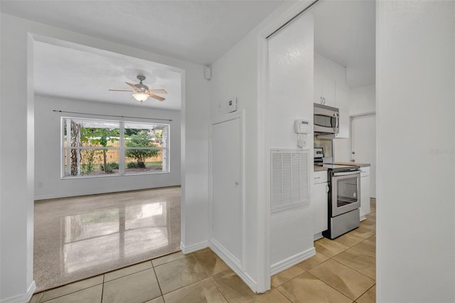 kitchen featuring ceiling fan, white cabinetry, light tile patterned floors, and appliances with stainless steel finishes