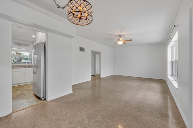 unfurnished living room with ceiling fan with notable chandelier