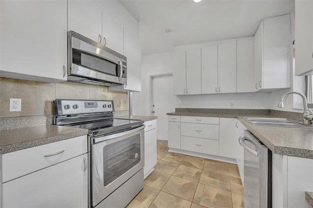 kitchen with sink, appliances with stainless steel finishes, tasteful backsplash, light tile patterned flooring, and white cabinetry