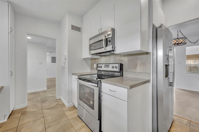 kitchen with backsplash, white cabinetry, light tile patterned flooring, and appliances with stainless steel finishes