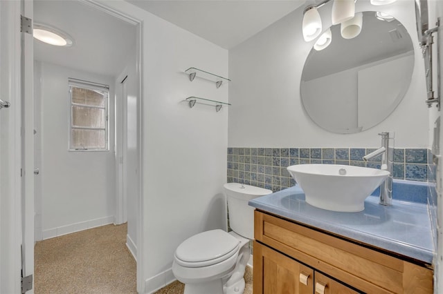 bathroom with vanity, toilet, and tile walls