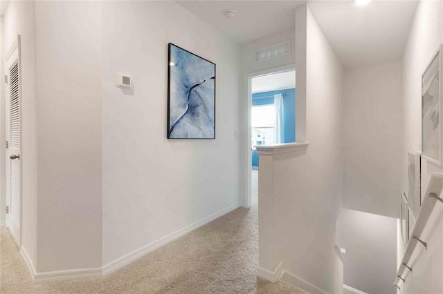 hallway featuring light colored carpet