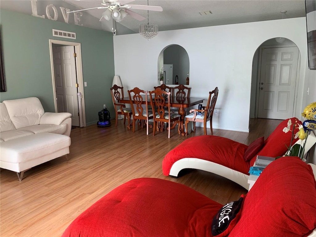 living room with ceiling fan with notable chandelier and wood-type flooring