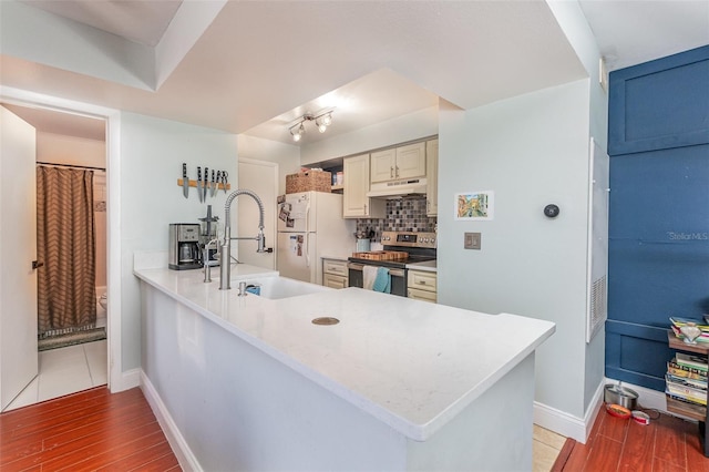 kitchen featuring backsplash, electric stove, kitchen peninsula, and light hardwood / wood-style flooring