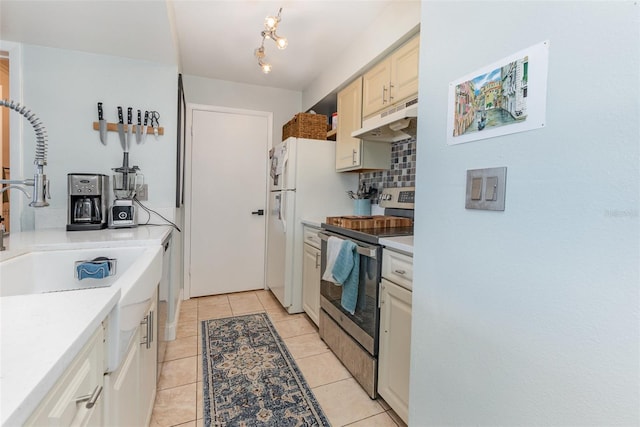 kitchen with stainless steel electric range, sink, light tile patterned floors, and backsplash