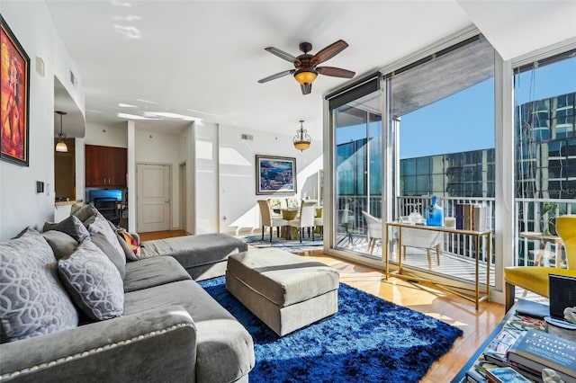 living room featuring hardwood / wood-style floors, ceiling fan, and a wall of windows