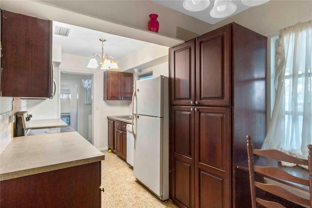 kitchen with a chandelier, pendant lighting, and white appliances