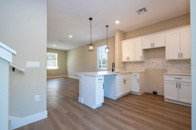 kitchen featuring kitchen peninsula, light wood-type flooring, white cabinetry, and sink