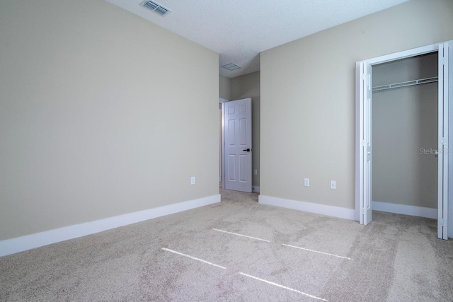 unfurnished bedroom featuring a textured ceiling, light carpet, and a closet